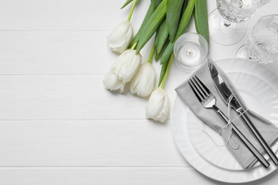 Stylish setting with cutlery and tulips on white wooden table, flat lay. Space for text