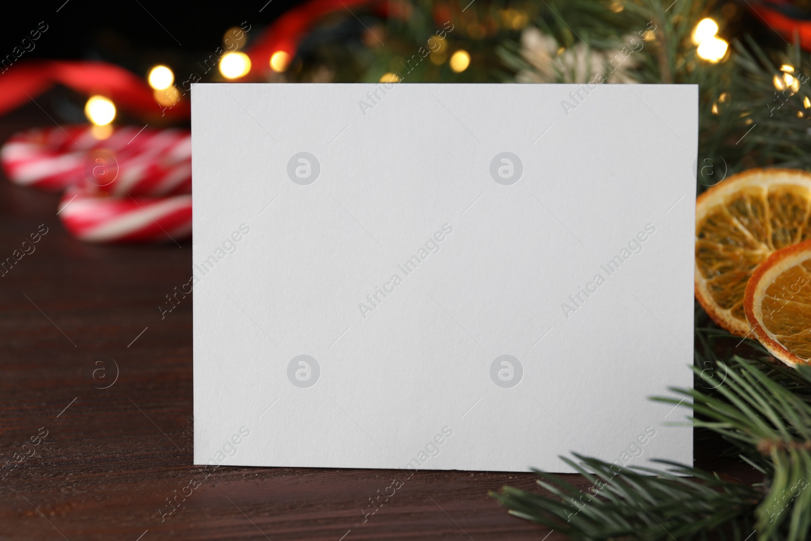 Photo of Blank greeting card near Christmas decorations on wooden table, closeup. Space for text