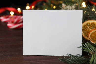 Photo of Blank greeting card near Christmas decorations on wooden table, closeup. Space for text