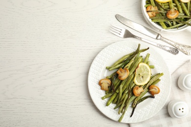 Photo of Delicious baked green beans served on white table. Space for text