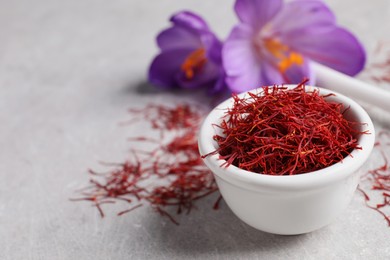 Photo of Dried saffron and crocus flowers on grey table, closeup. Space for text
