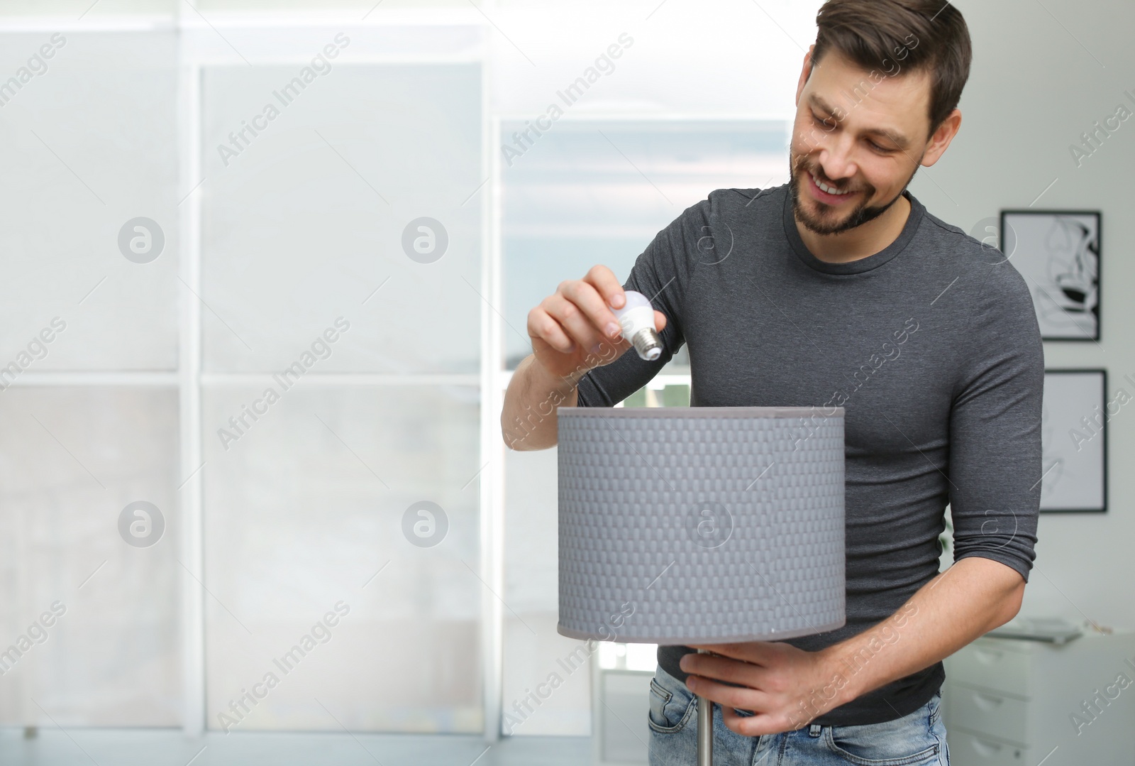 Photo of Man changing light bulb in lamp indoors