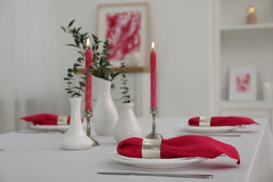 Beautiful table setting with green branches in vases and burning candles indoors. Stylish dining room