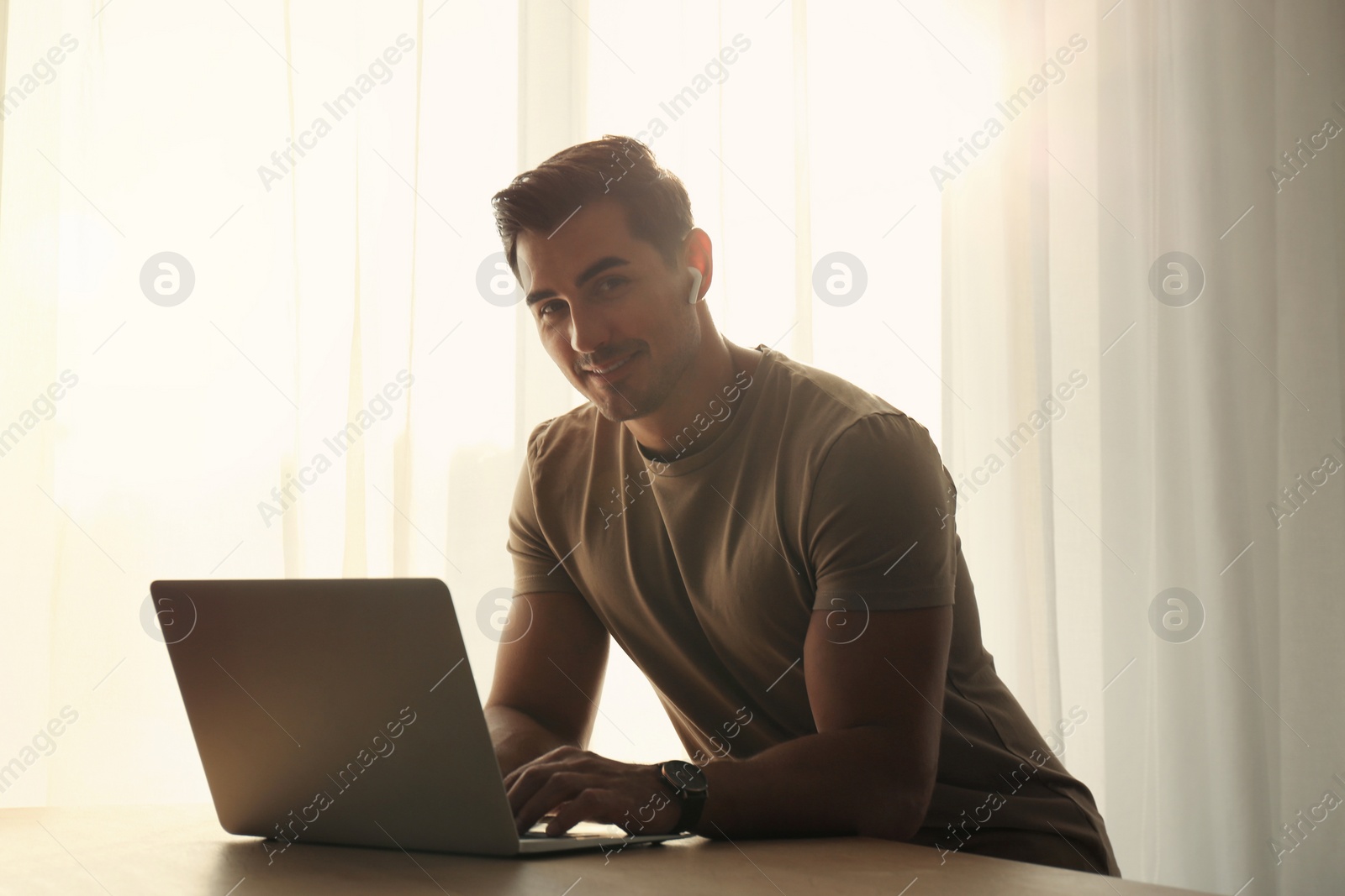 Photo of Portrait of young man with laptop at table indoors