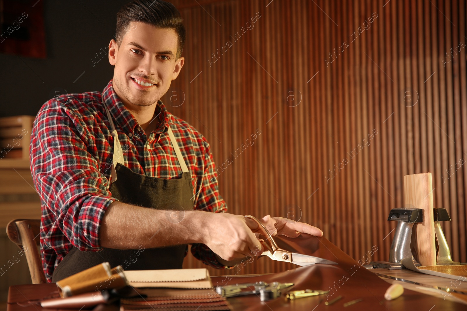 Photo of Man cutting leather with scissors in workshop