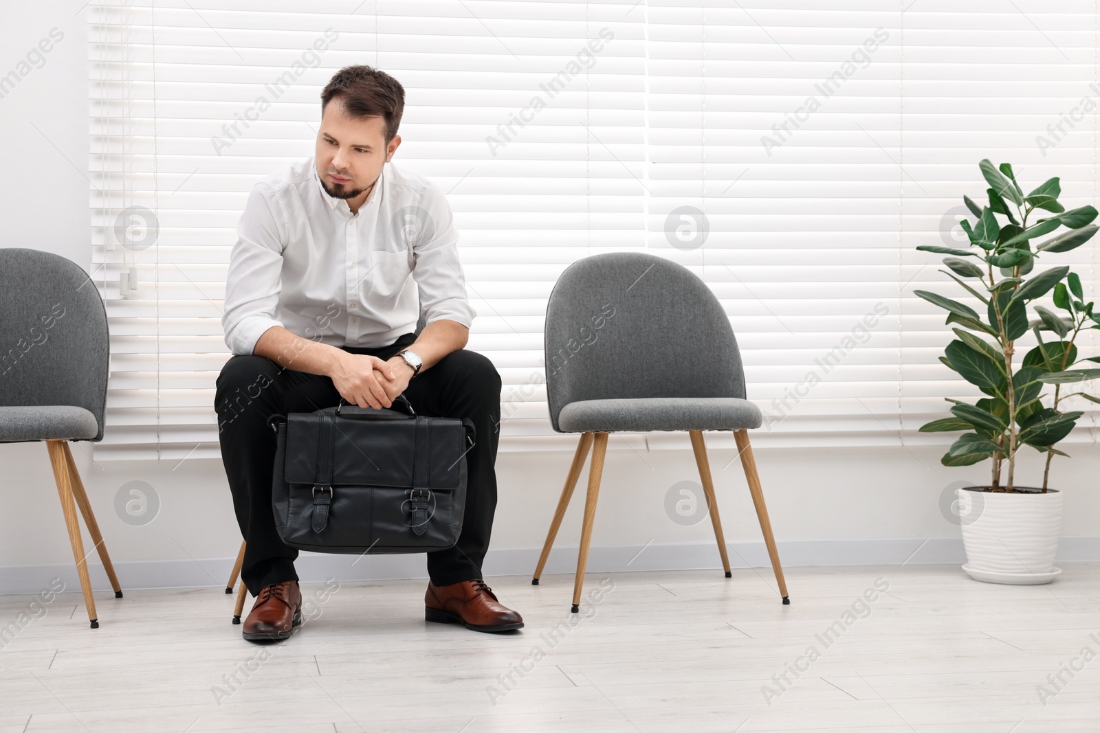 Photo of Man sitting on chair and waiting for job interview indoors