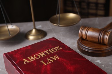 Abortion Law book, scales of justice and gavel on brown marble table