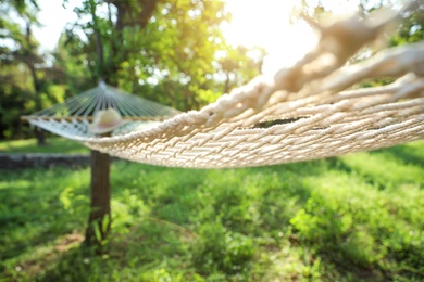 Photo of Comfortable net hammock with pillow and hat hanging in green garden
