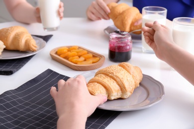 Women having tasty breakfast with fresh croissants at table