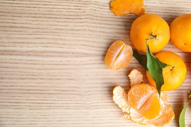 Photo of Fresh ripe tangerines and space for text on wooden background, top view