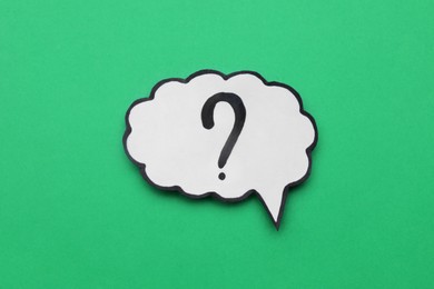 Photo of Paper speech bubble with question mark on green background, top view