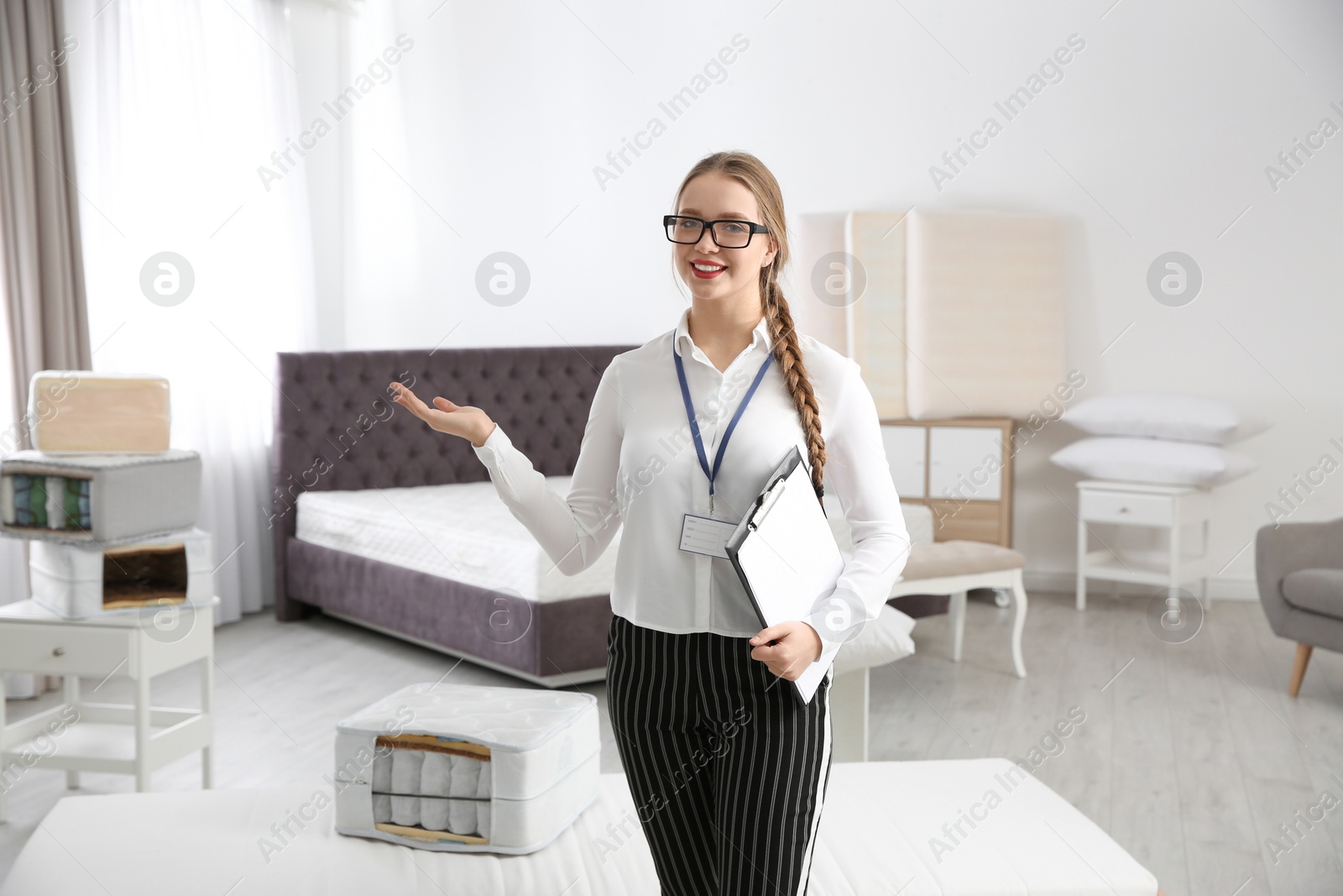 Photo of Young saleswoman with clipboard in mattress store