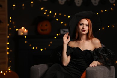 Photo of Young woman in scary witch costume against blurred lights indoors, space for text. Halloween celebration