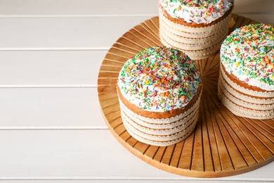 Photo of Traditional Easter cakes with sprinkles on white wooden table. Space for text
