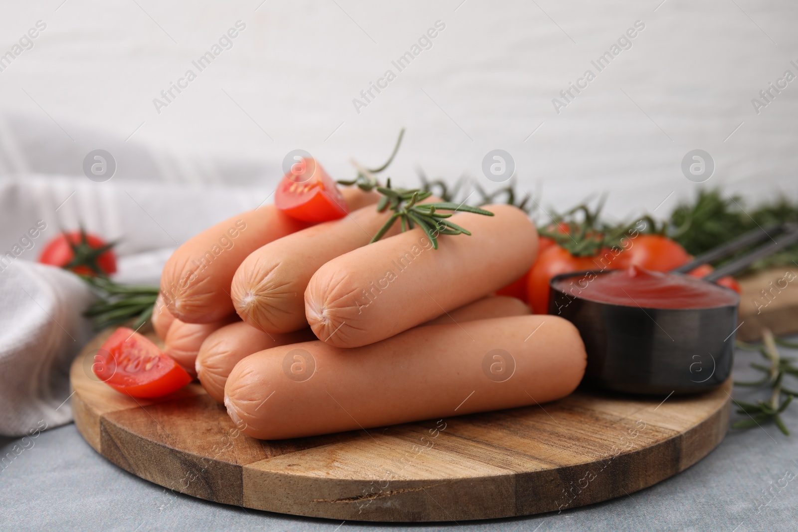 Photo of Delicious boiled sausages, tomato sauce, tomatoes and rosemary on gray table, closeup