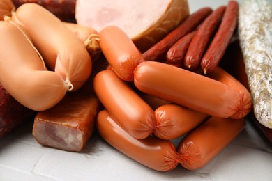 Photo of Different types of sausages on white textured table, closeup