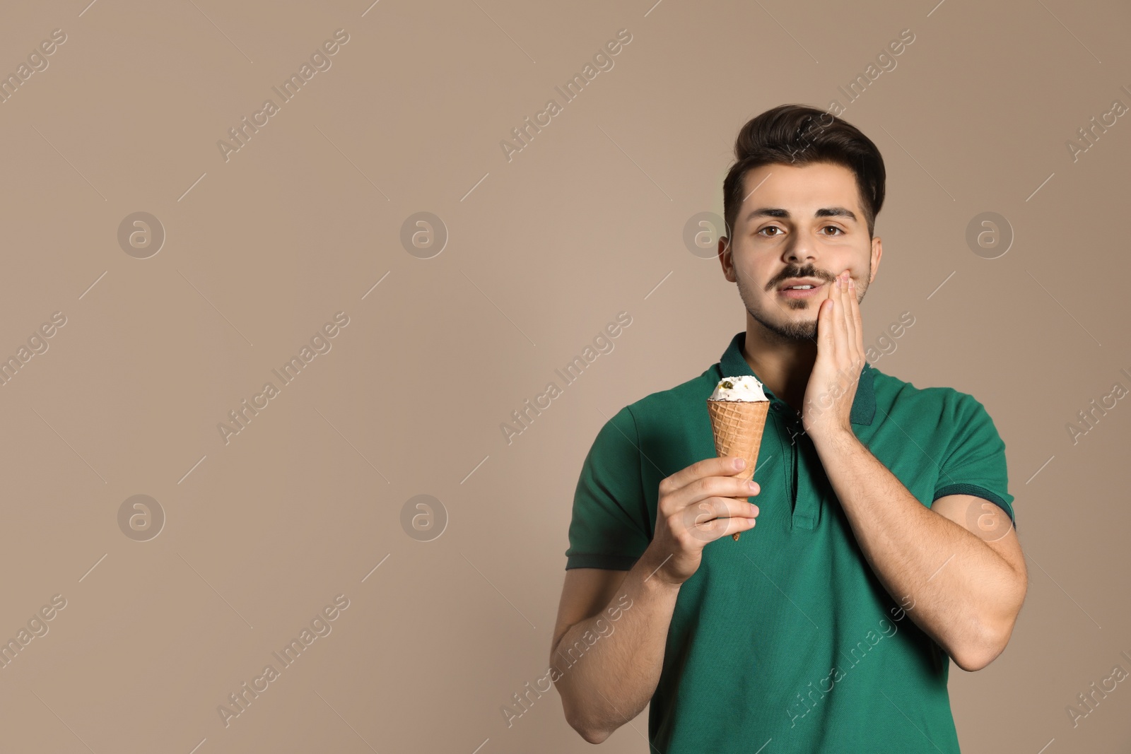 Photo of Young man with sensitive teeth and ice cream on color background. Space for text