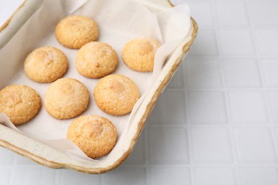 Photo of Tasty sweet sugar cookies in baking dish on white tiled table, closeup. Space for text