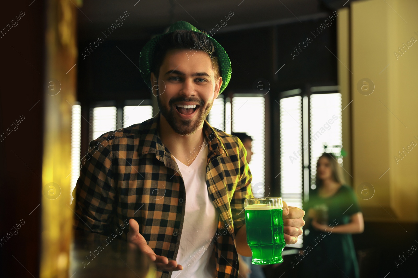 Photo of Young man with glass of green beer in pub. St. Patrick's Day celebration