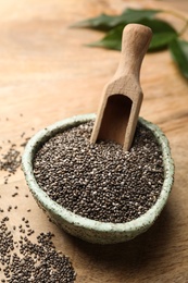 Bowl with chia seeds and scoop on wooden table