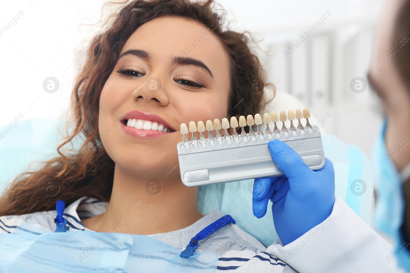 Photo of Dentist matching patient's teeth color with palette in office