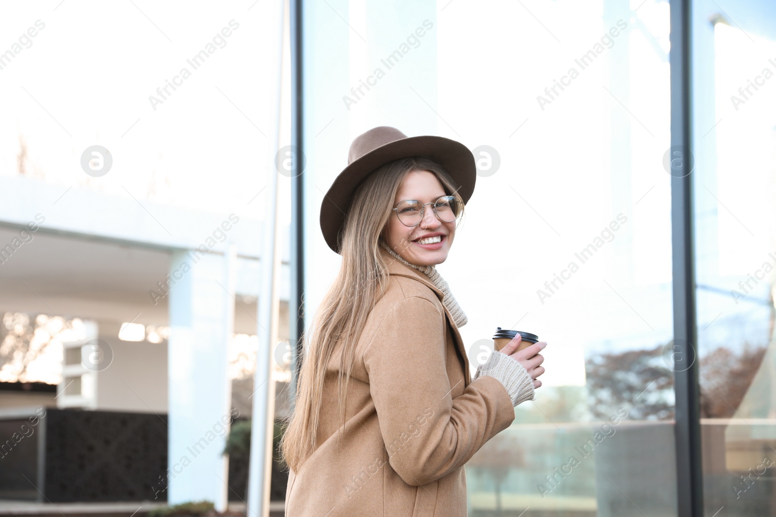 Photo of Young woman with cup of coffee on city street in morning