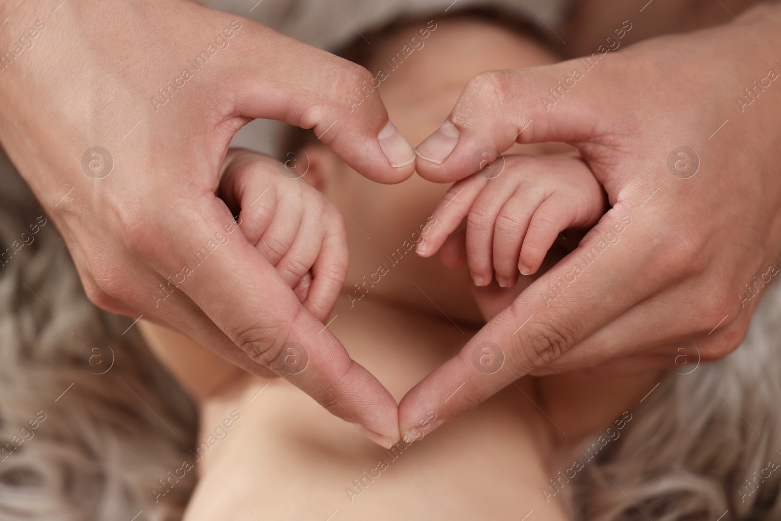 Photo of Father with his newborn baby, closeup. Man making heart shape with hands. Lovely family