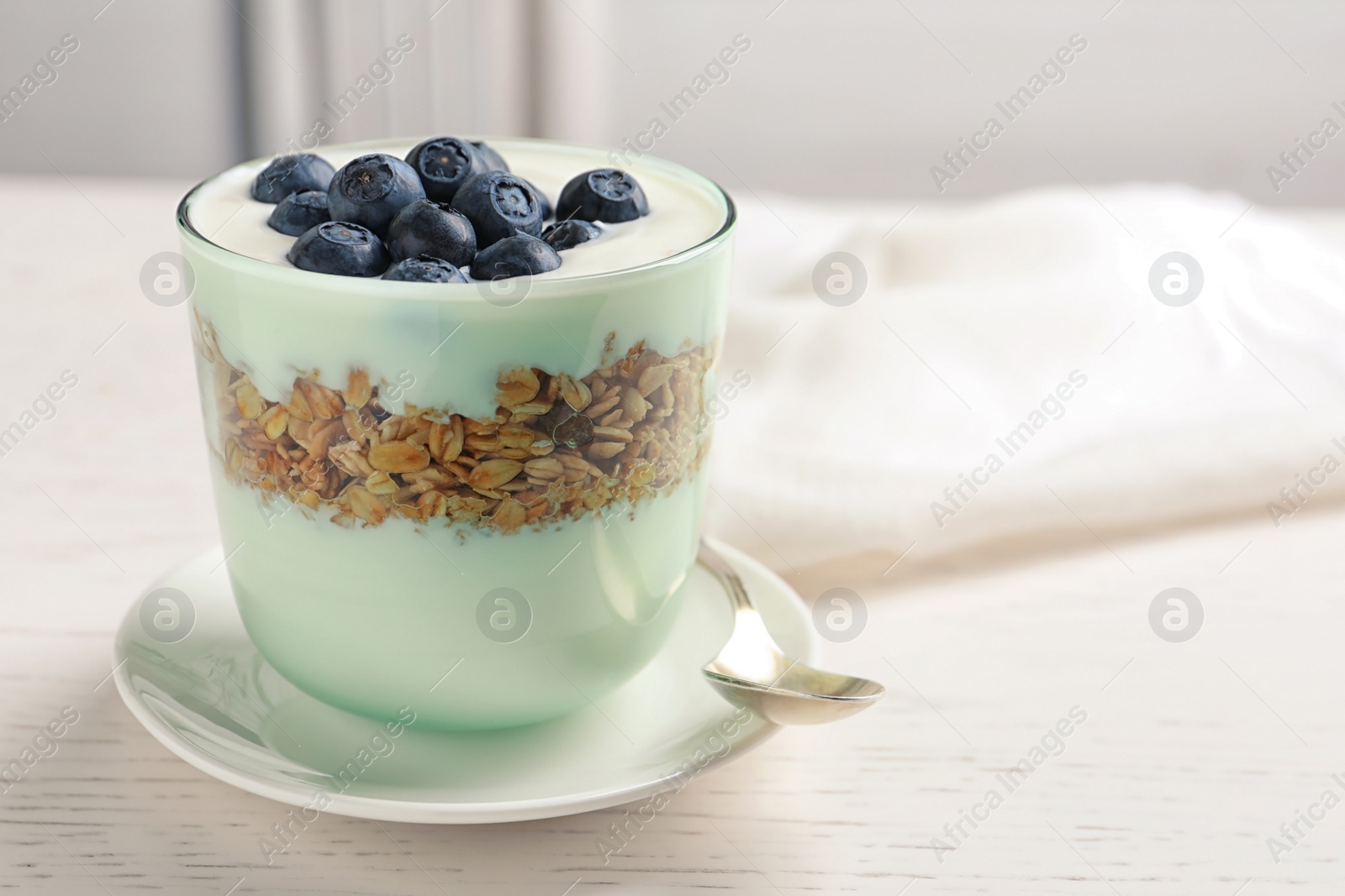 Photo of Glass with yogurt, berries and granola on table