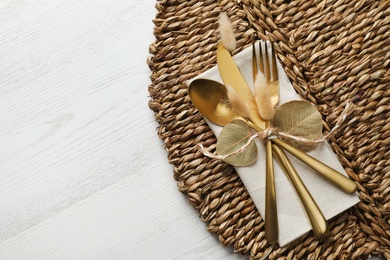 Autumn table setting, space for text. Cutlery and wicker mat on white wooden background, flat lay