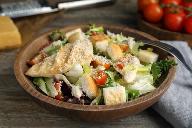 Photo of Delicious Caesar salad in bowl on wooden table, closeup