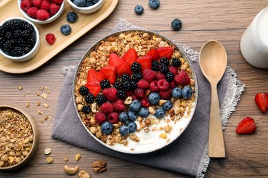 Healthy muesli served with berries on wooden table, flat lay