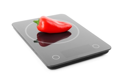 Ripe bell pepper on kitchen scales against white background