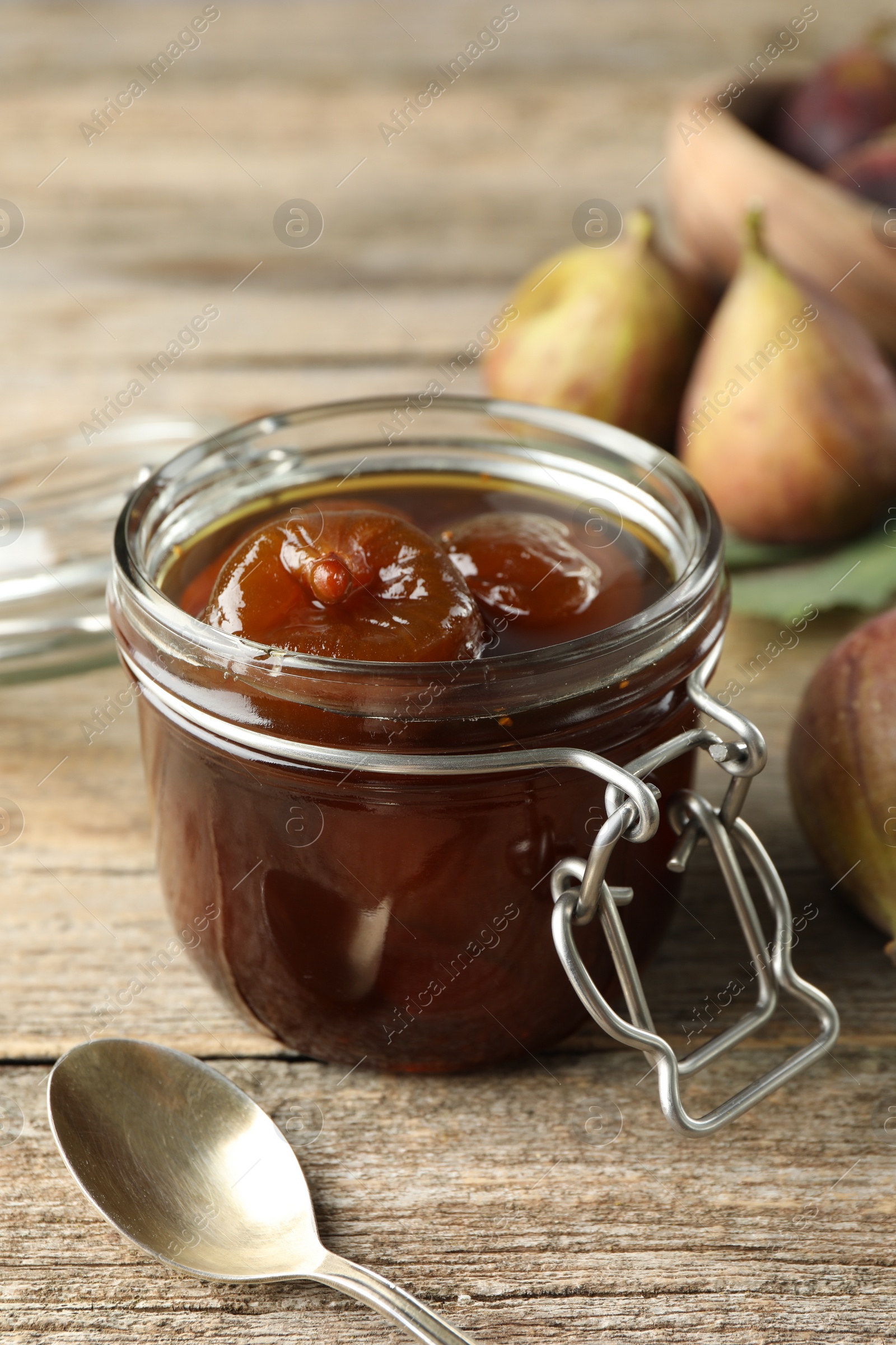 Photo of Jar of tasty sweet fig jam on wooden table