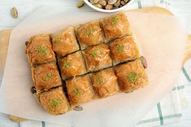 Delicious sweet baklava with pistachios on white table, flat lay