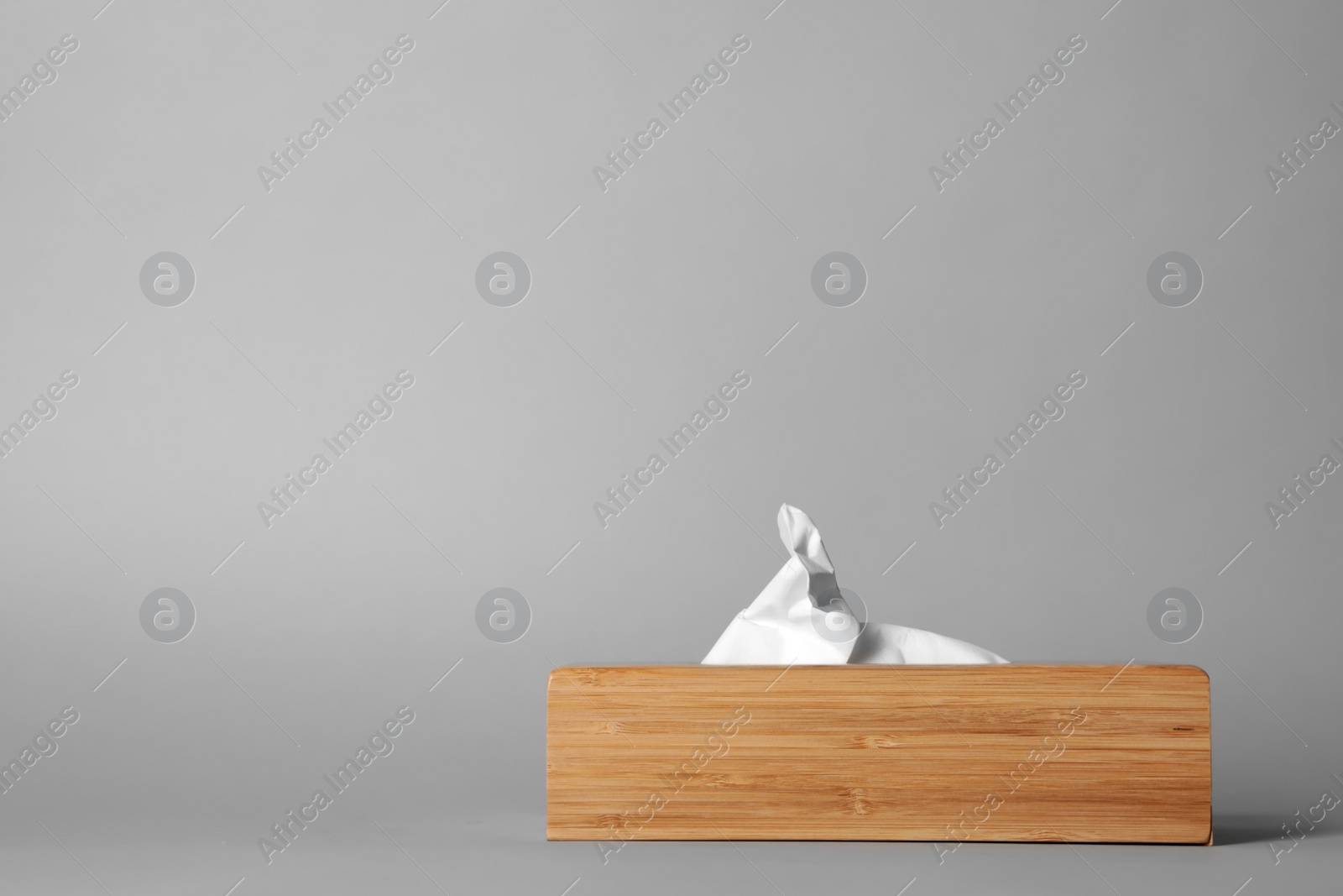 Photo of Napkin holder with paper serviettes on gray background. Space for text