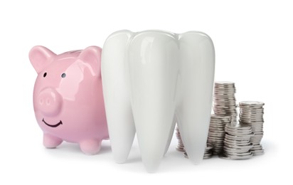 Photo of Ceramic model of tooth, piggy bank and coins on white background. Expensive treatment