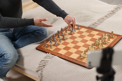 Teacher near chessboard conducting online lesson at home, closeup. Time for hobby