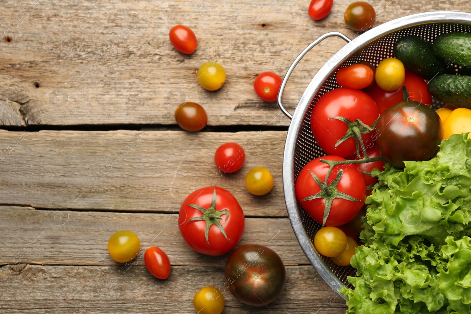 Photo of Fresh vegetables in colander on wooden table, flat lay. Space for text