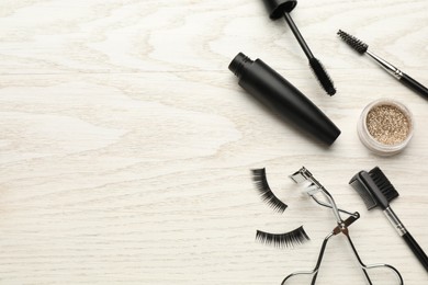 Photo of Flat lay composition with eyelash curler, makeup products and accessories on white wooden table. Space for text