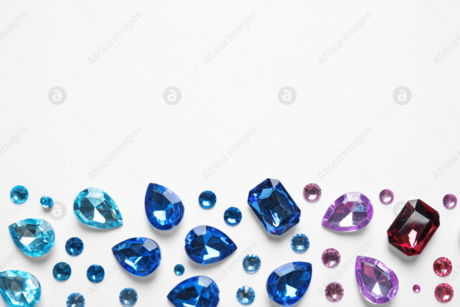 Photo of Different beautiful gemstones on white background, top view