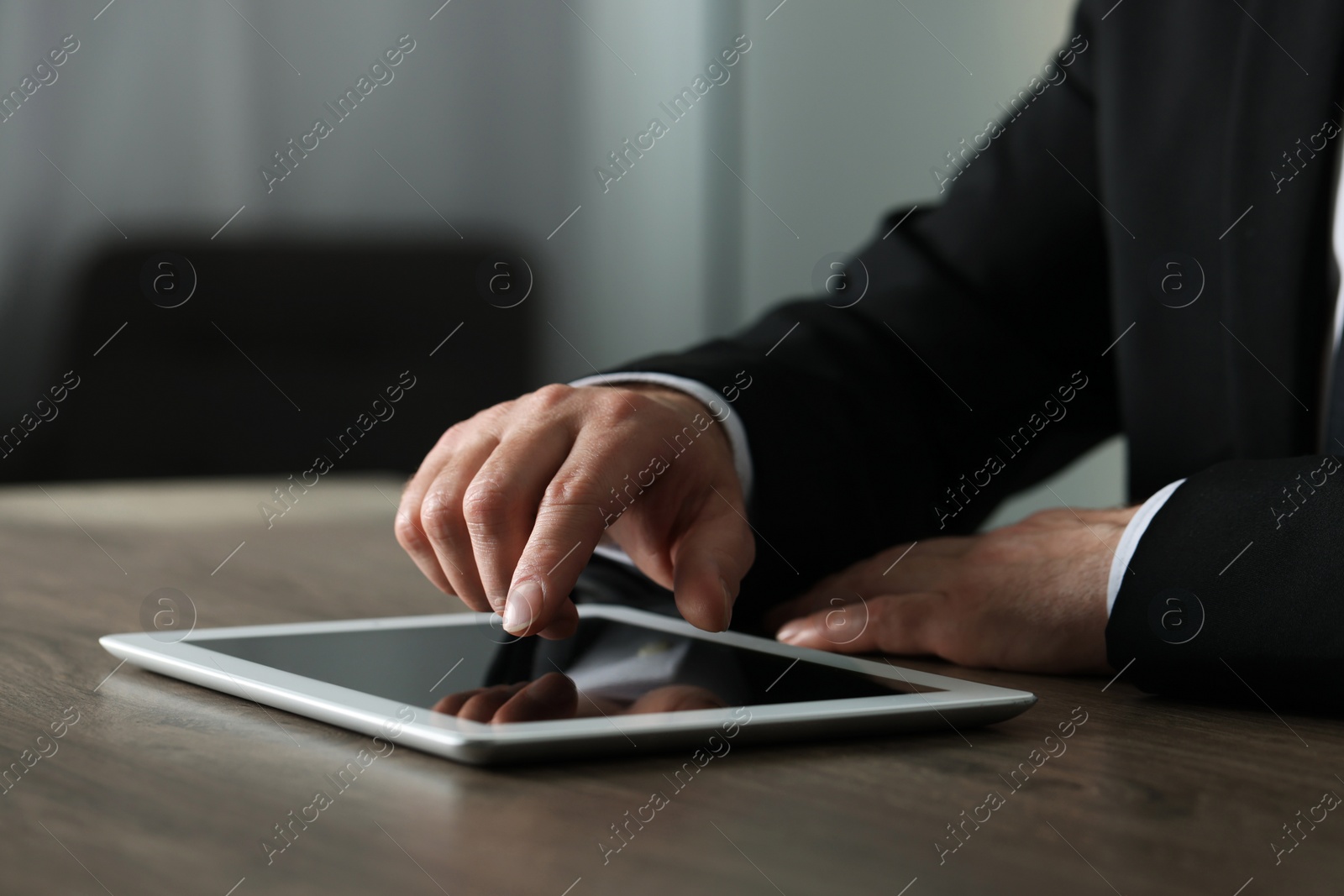 Photo of Closeup view of man using new tablet at wooden desk indoors