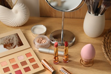 Photo of Makeup products and mirror on wooden dressing table
