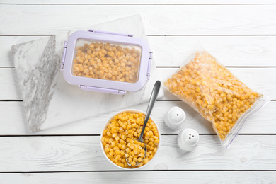 Flat lay composition with frozen sweet corn on white wooden table. Vegetable preservation