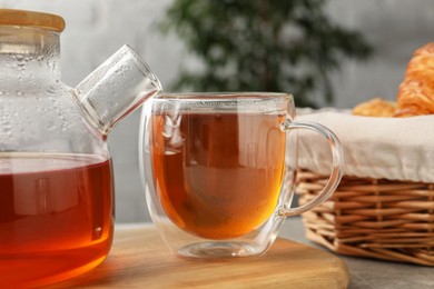 Photo of Aromatic tea in glass cup and teapot on table, closeup