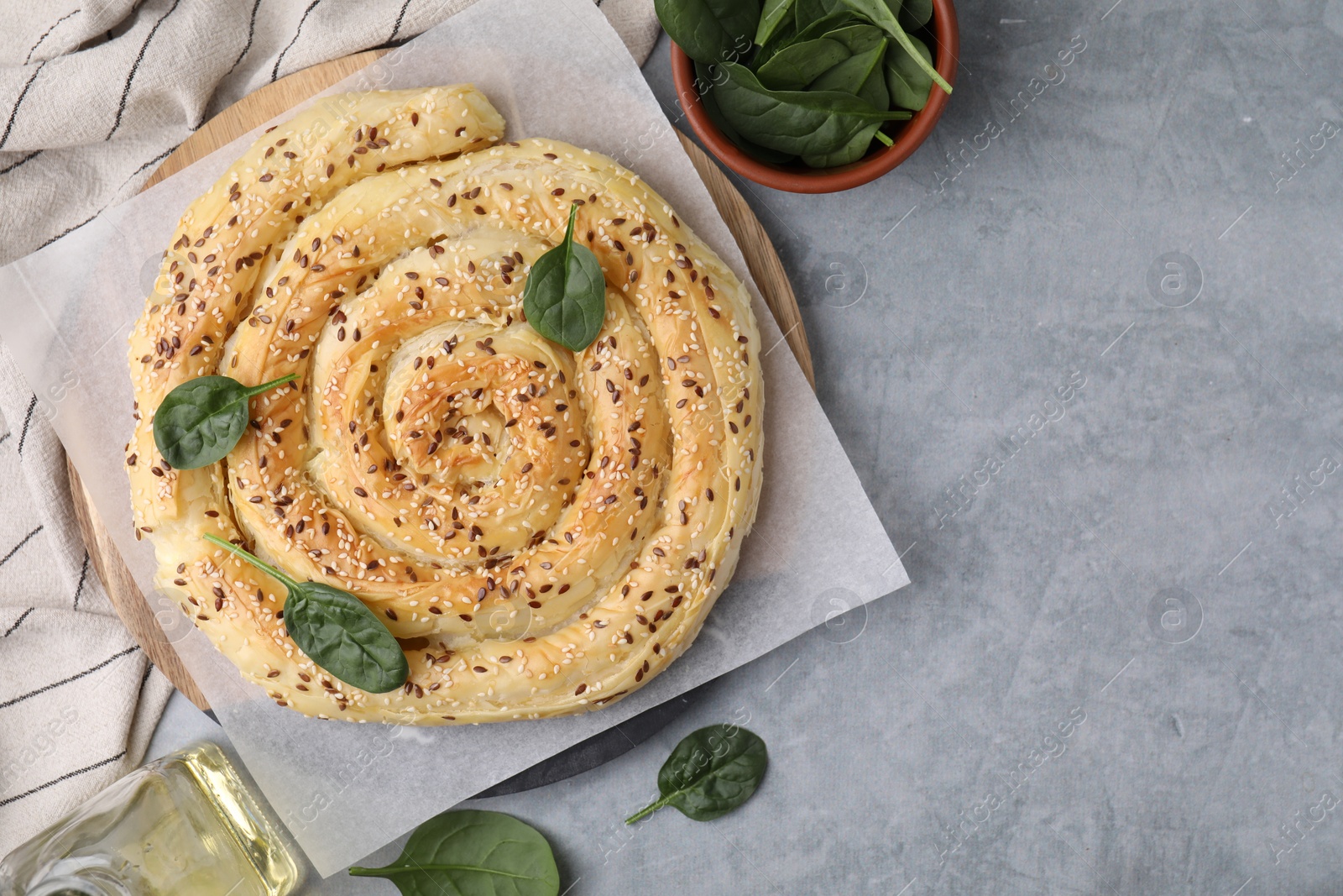 Photo of Delicious puff pastry with spinach on grey table, flat lay. Space for text