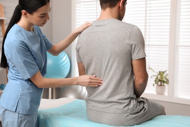 Photo of Orthopedist examining man's back in clinic. Scoliosis treatment