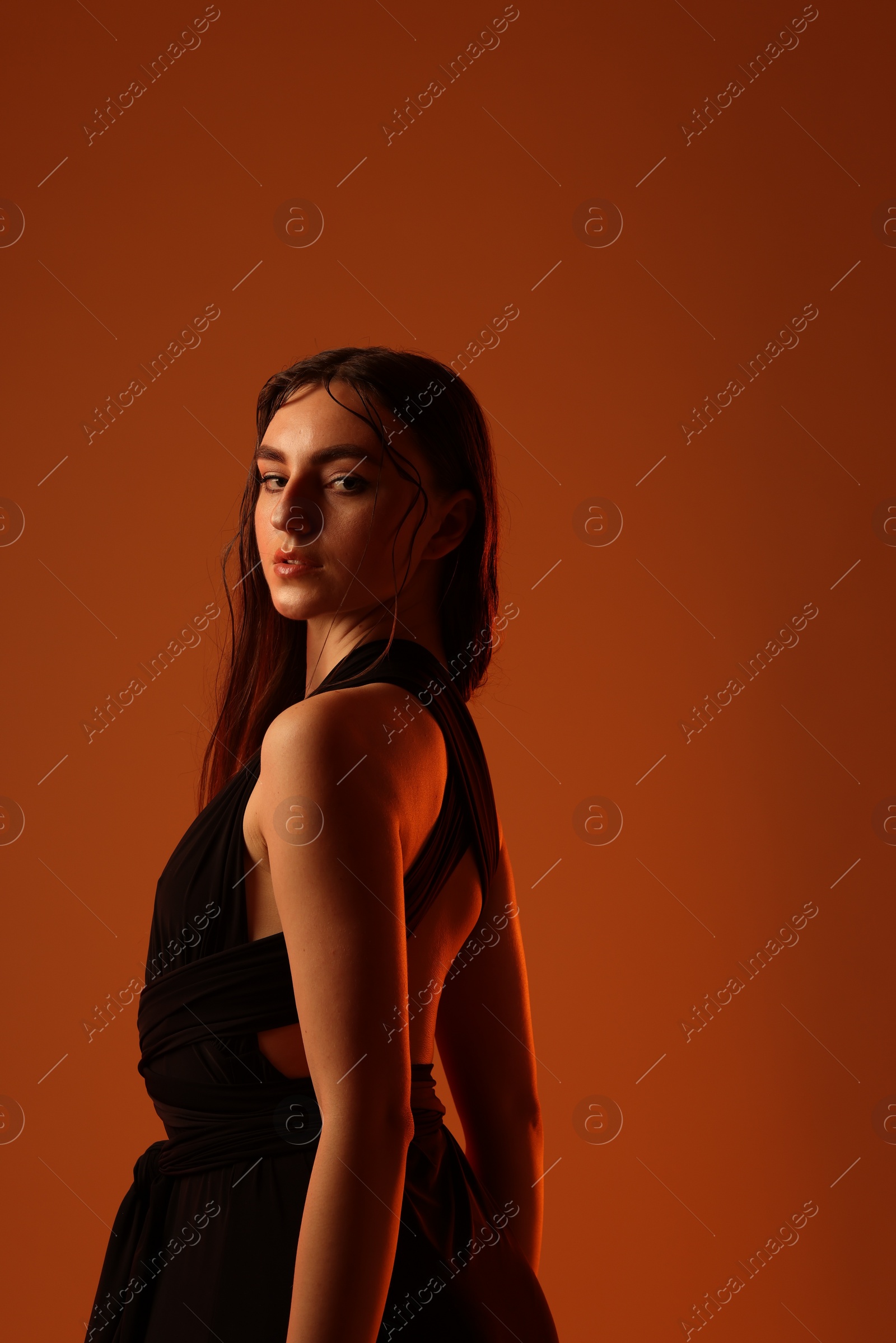 Photo of Beautiful woman in black dress posing on brown background