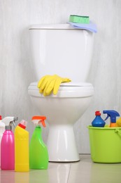 Photo of Different cleaning supplies and toilet bowl in bathroom