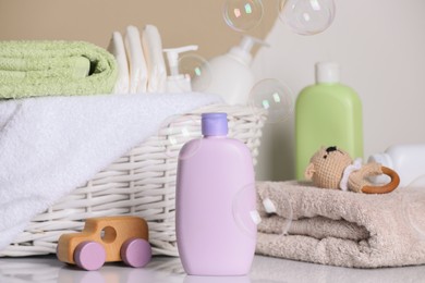 Baby cosmetic products, toys, diapers and soft towels on white table