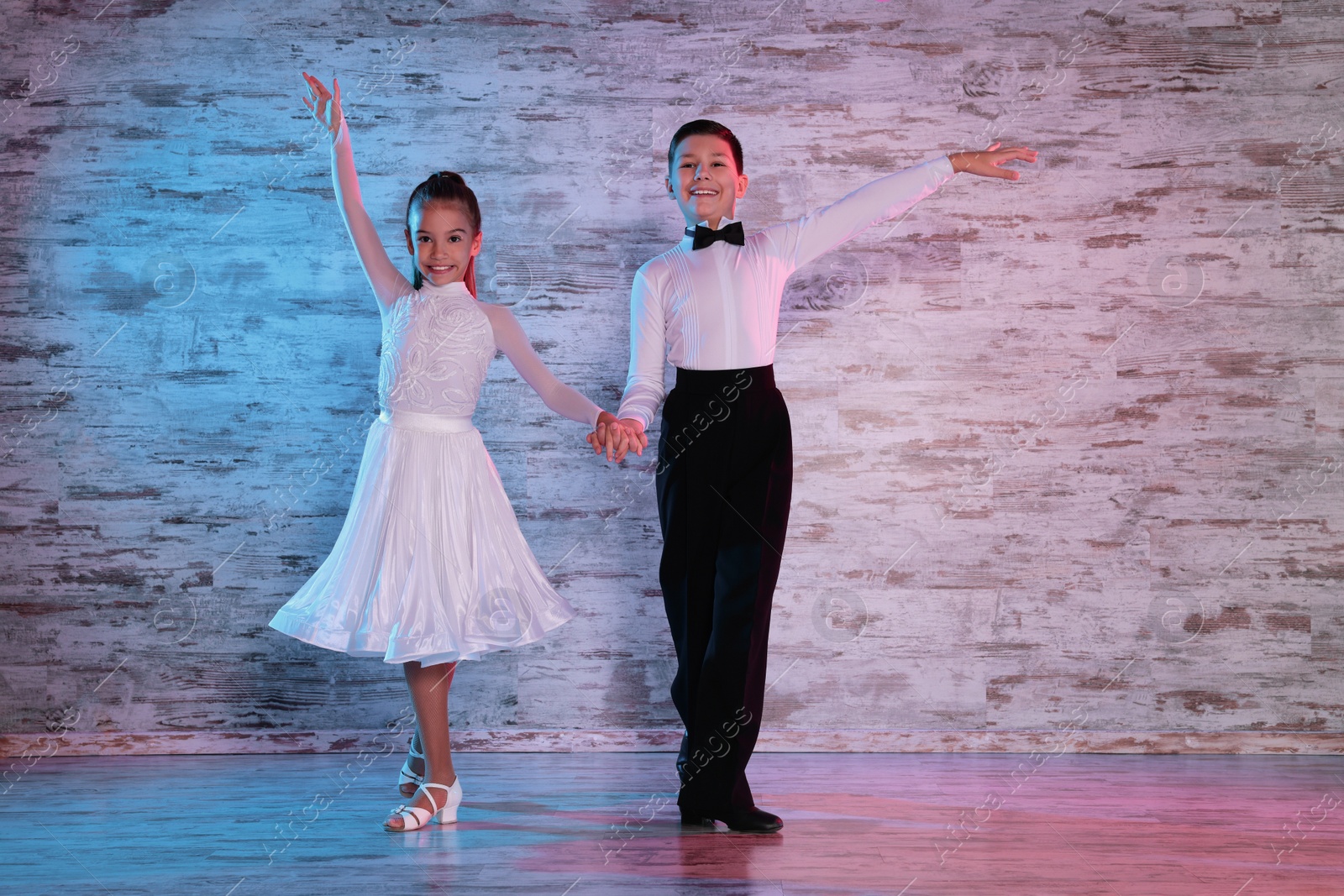 Photo of Beautifully dressed couple of kids dancing together in studio